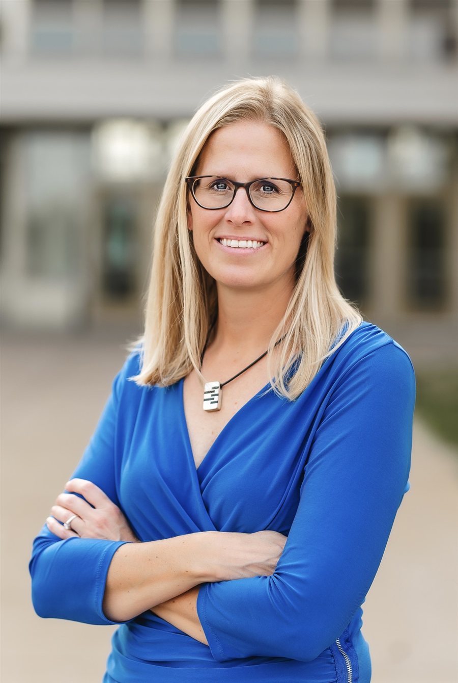 Carrie Tate, candidate for Hastings School Board, smiling in a blue dress